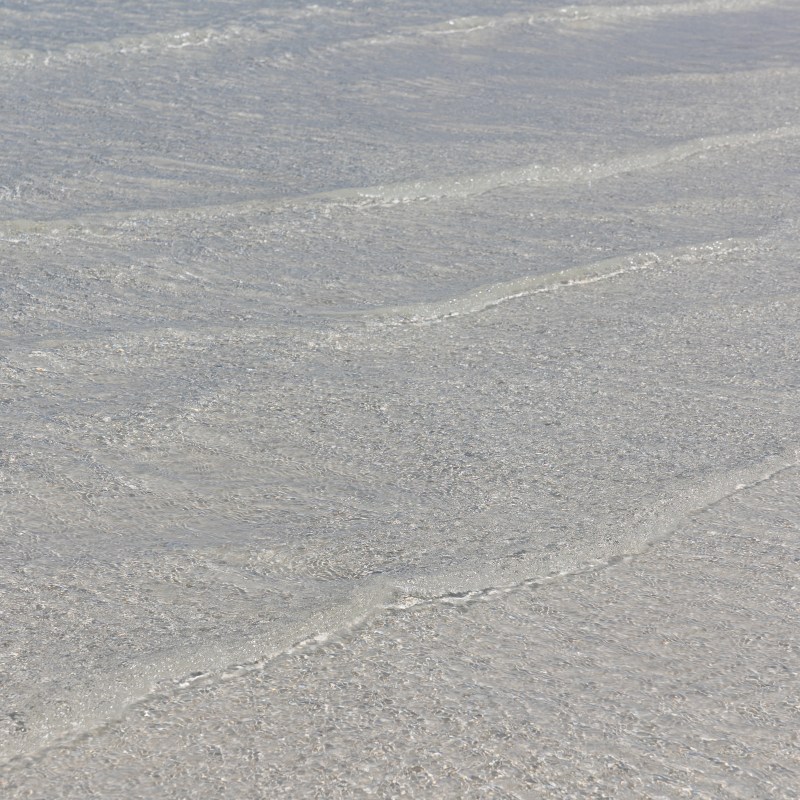 Gentle waves on a sandy beach with clear water.