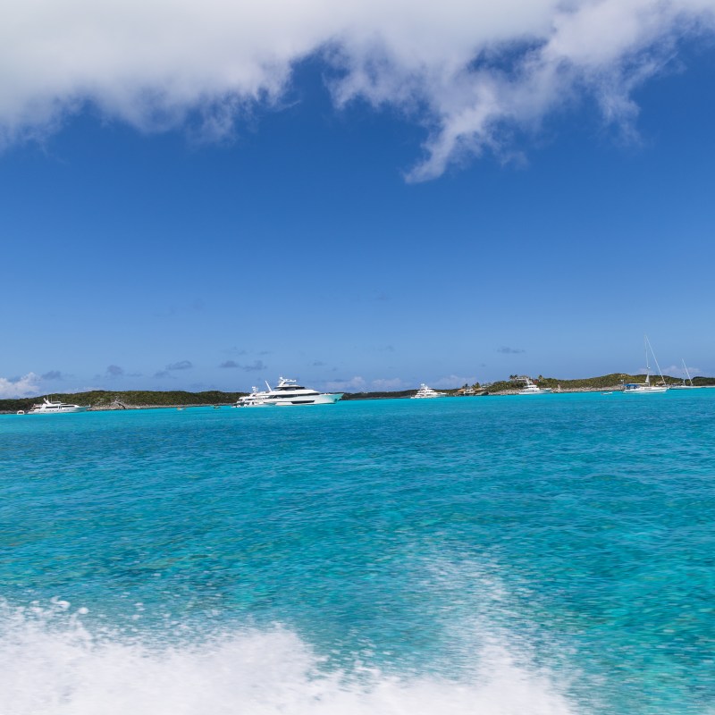 Blue ocean with boats under a clear sky.