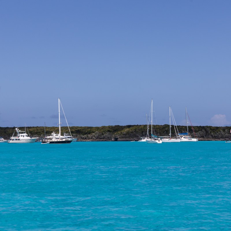Boats anchored in clear blue water under a blue sky.
