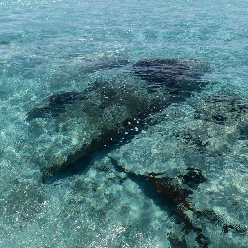 Clear blue water revealing submerged rocks.